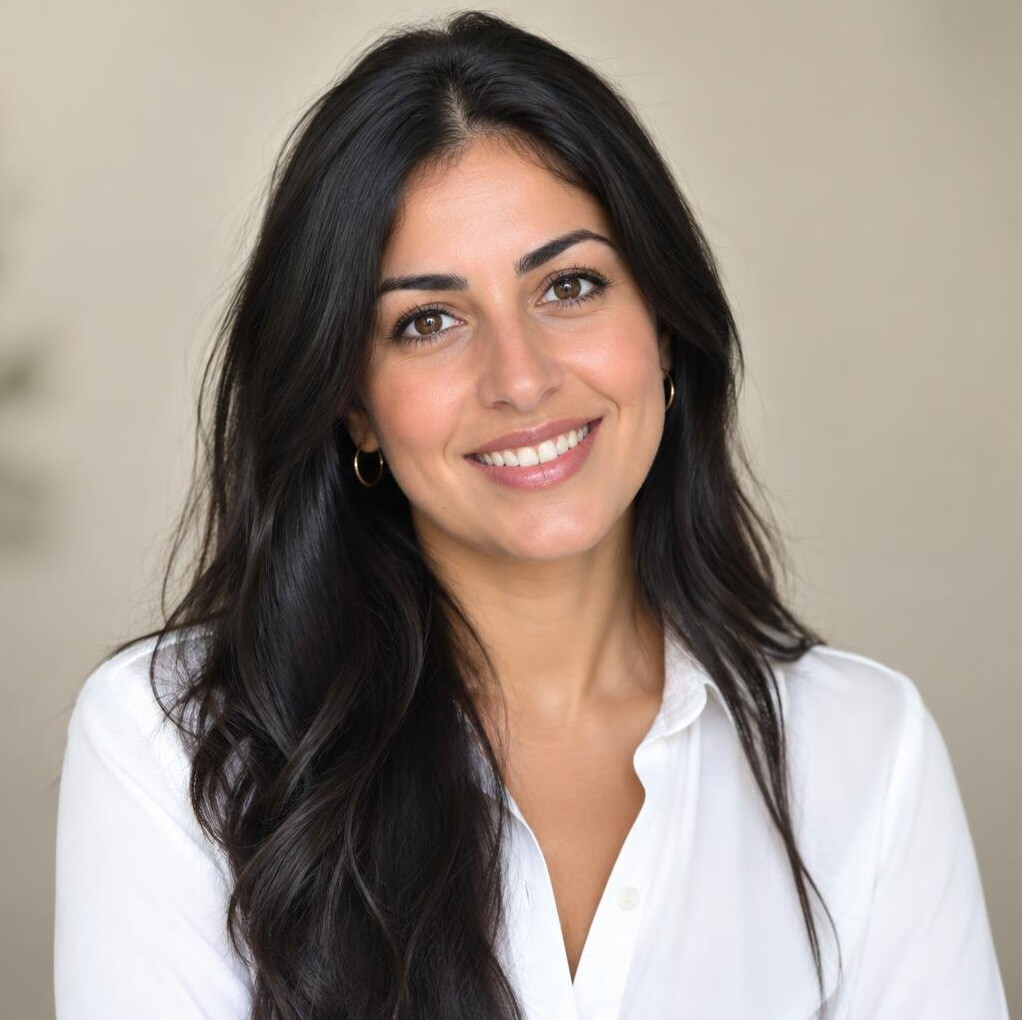 Portrait of a young woman with dark hair smiling in a white blouse